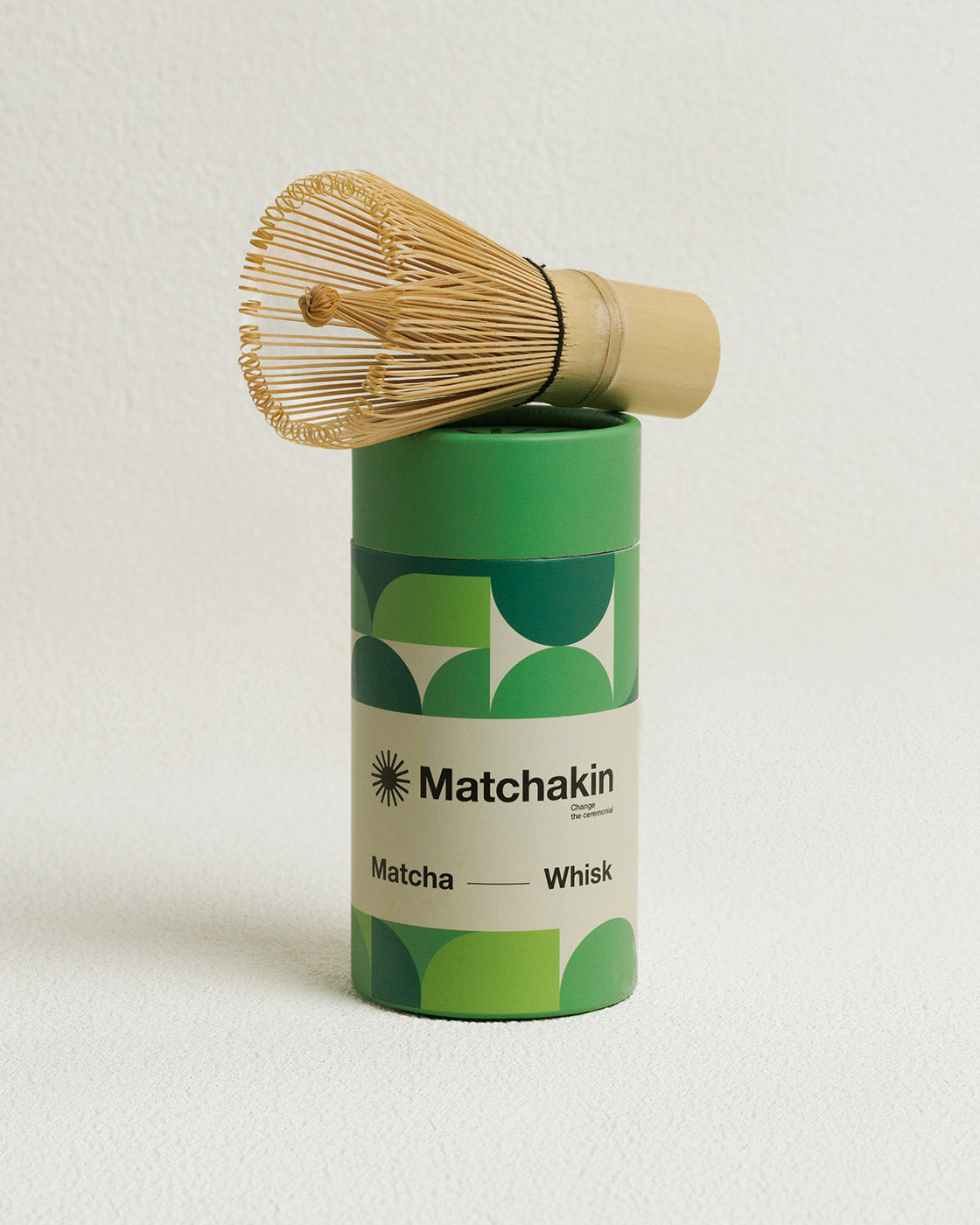 Matcha whisk with green cylindrical container labeled 'Matchakin' on a light background