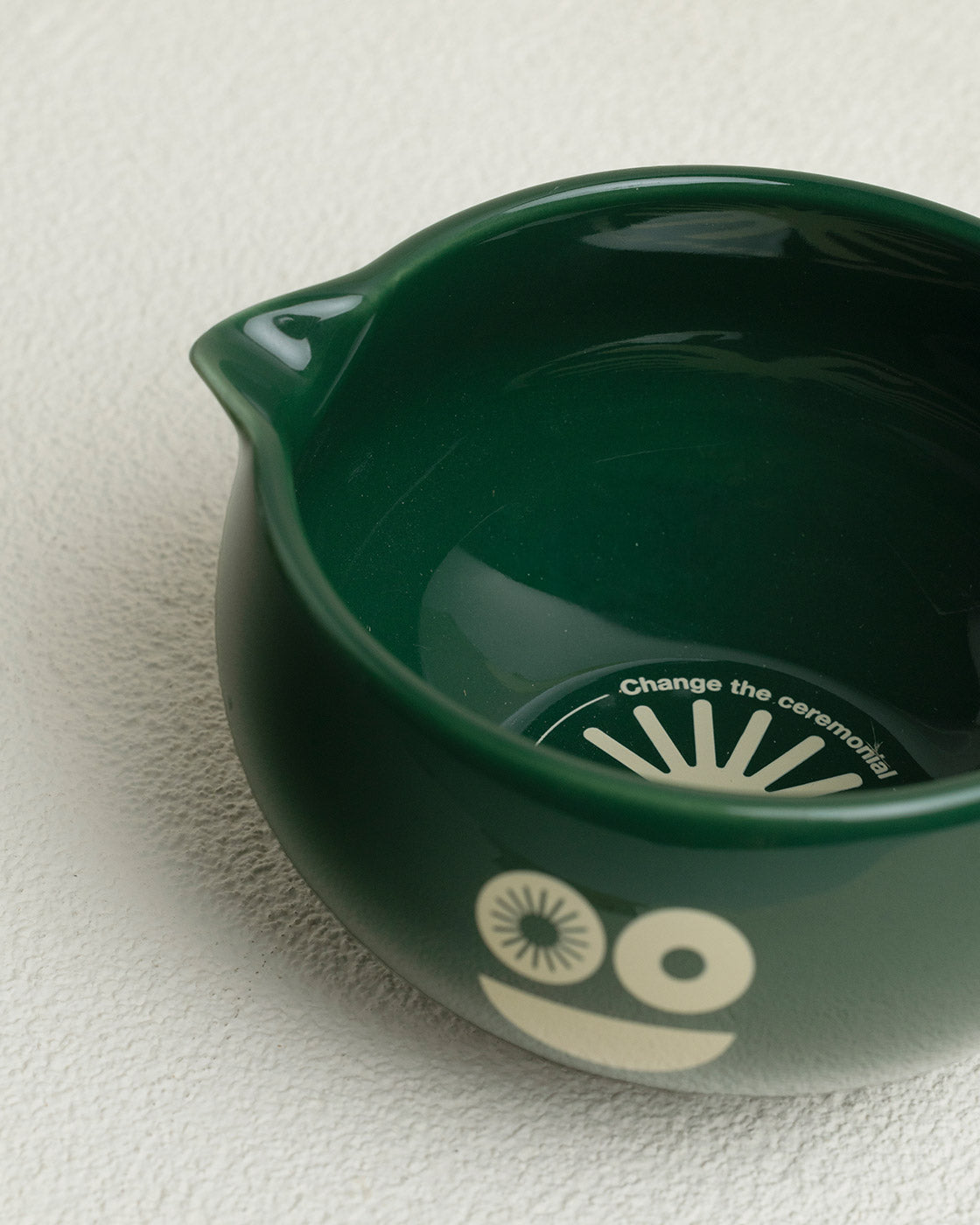 Green ceramic bowl with a face design on a white surface