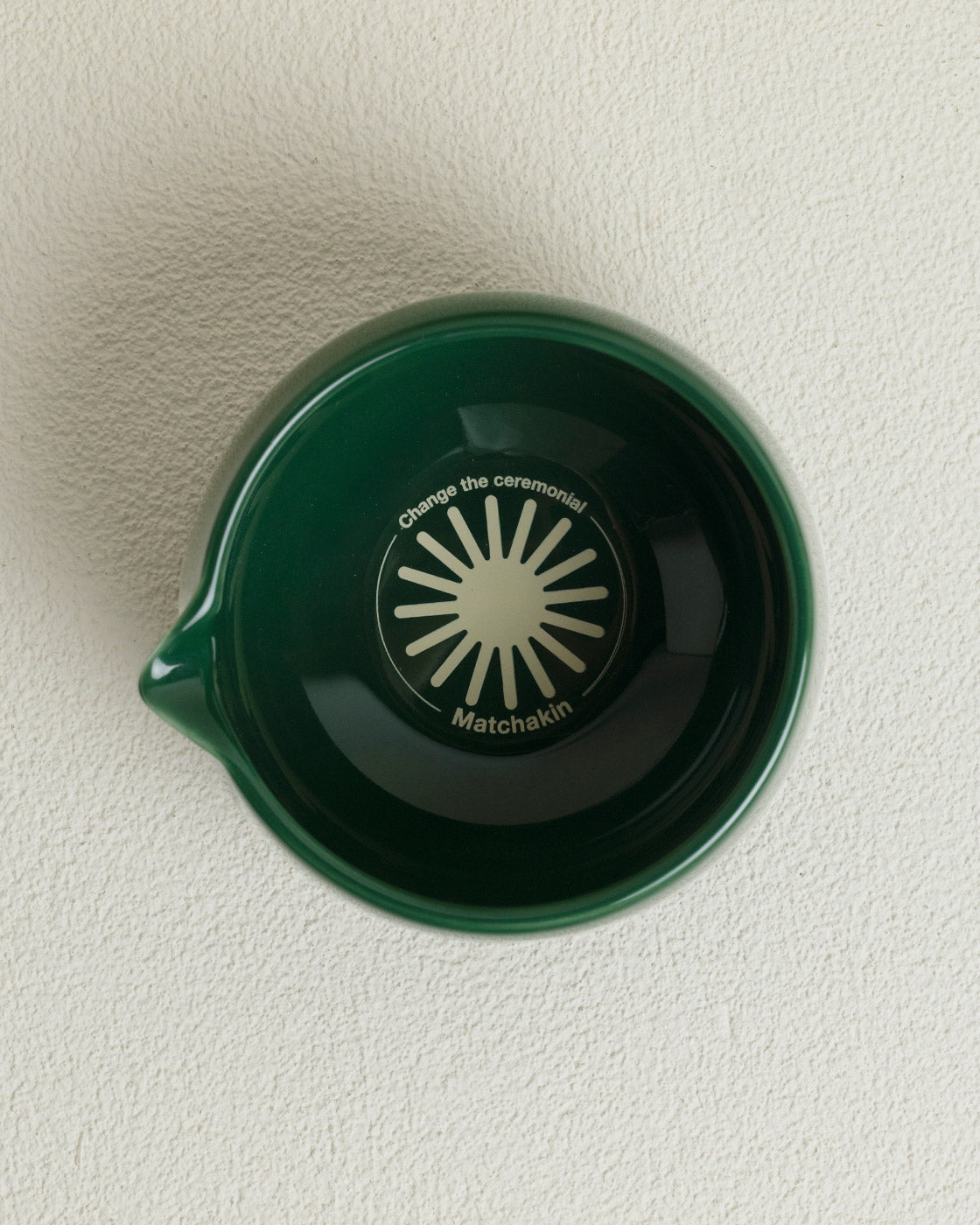 Green ceramic bowl with a face design on a white surface