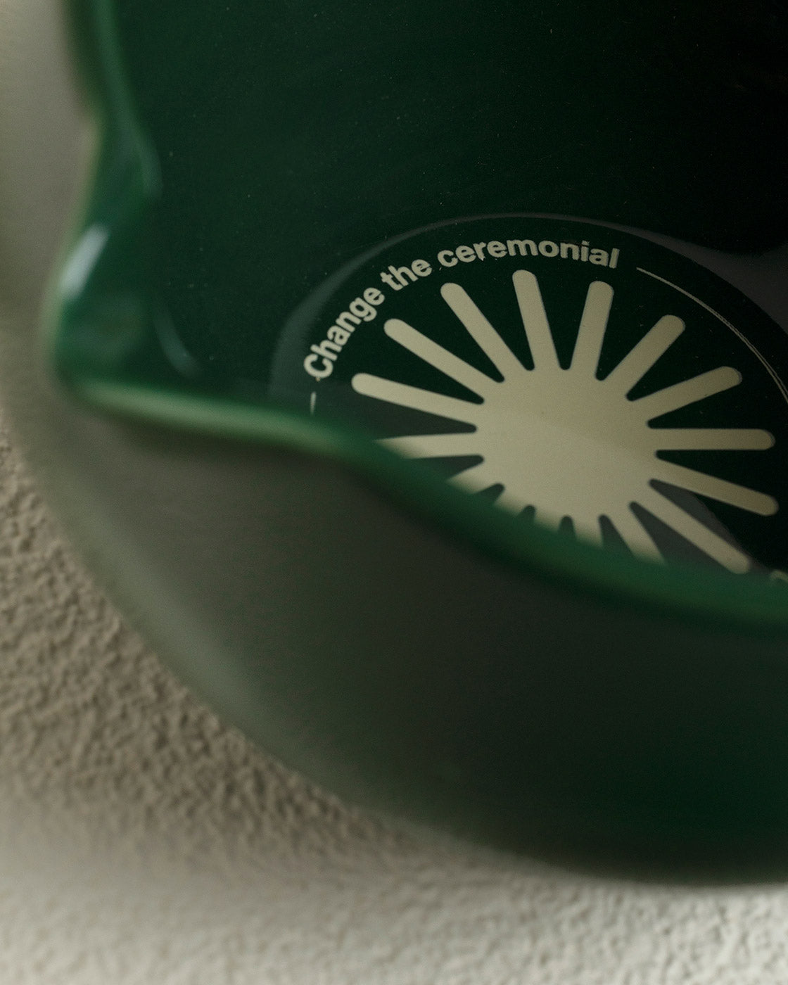 Green ceramic bowl with a decorative lid featuring text and a sun design.