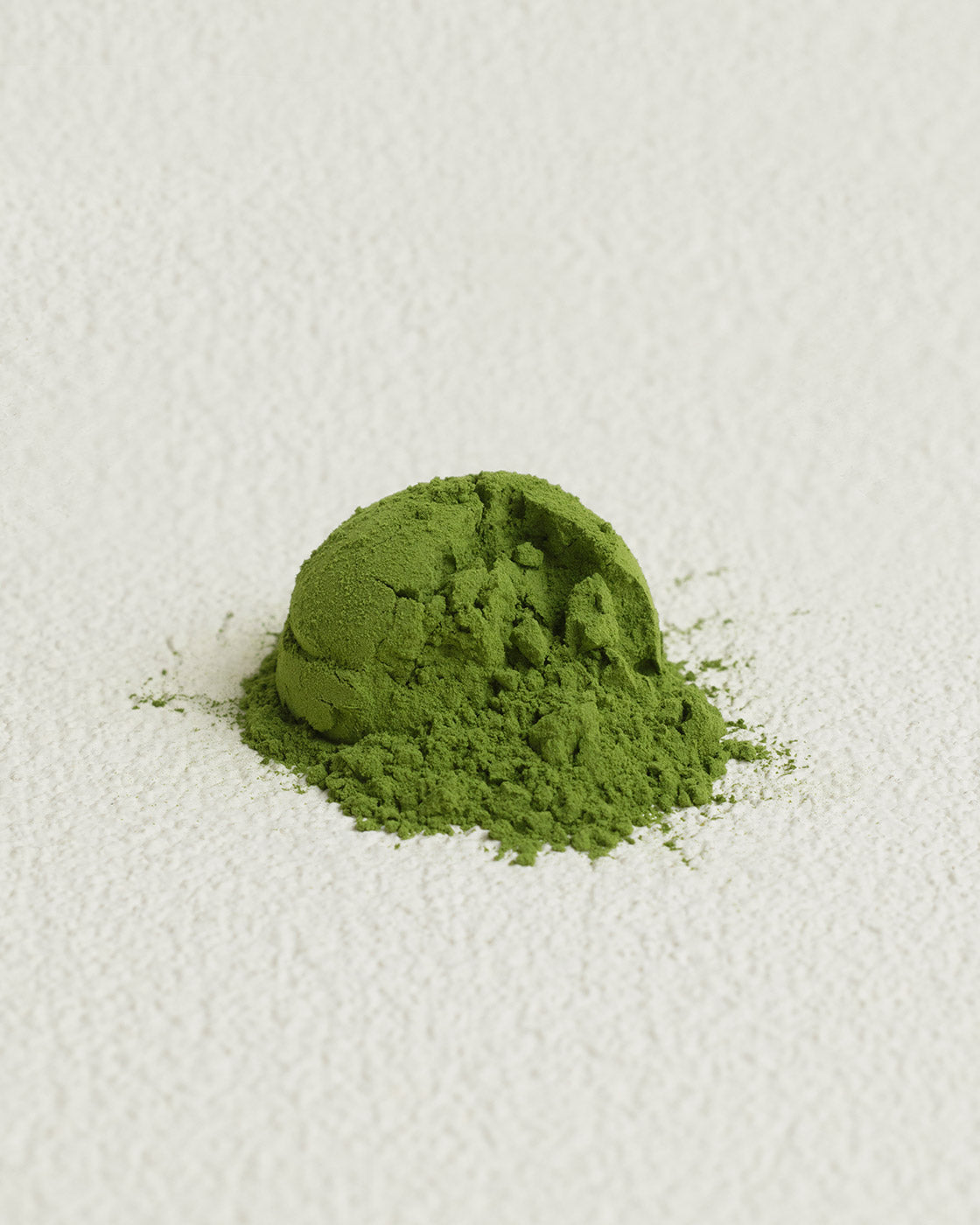 Green matcha powder on a white textured surface