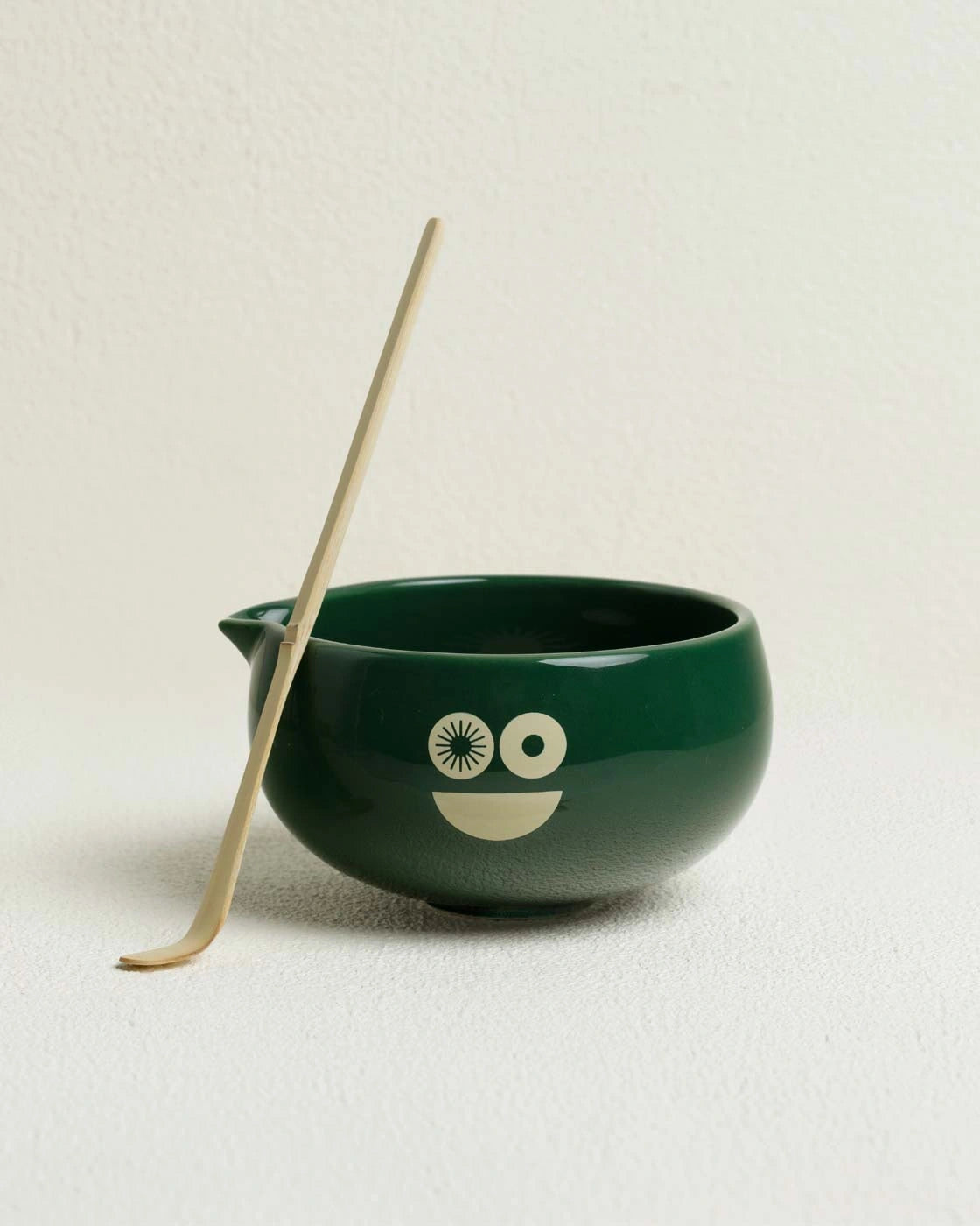 Green ceramic bowl with a face design and a bamboo spoon Matchakin matcha