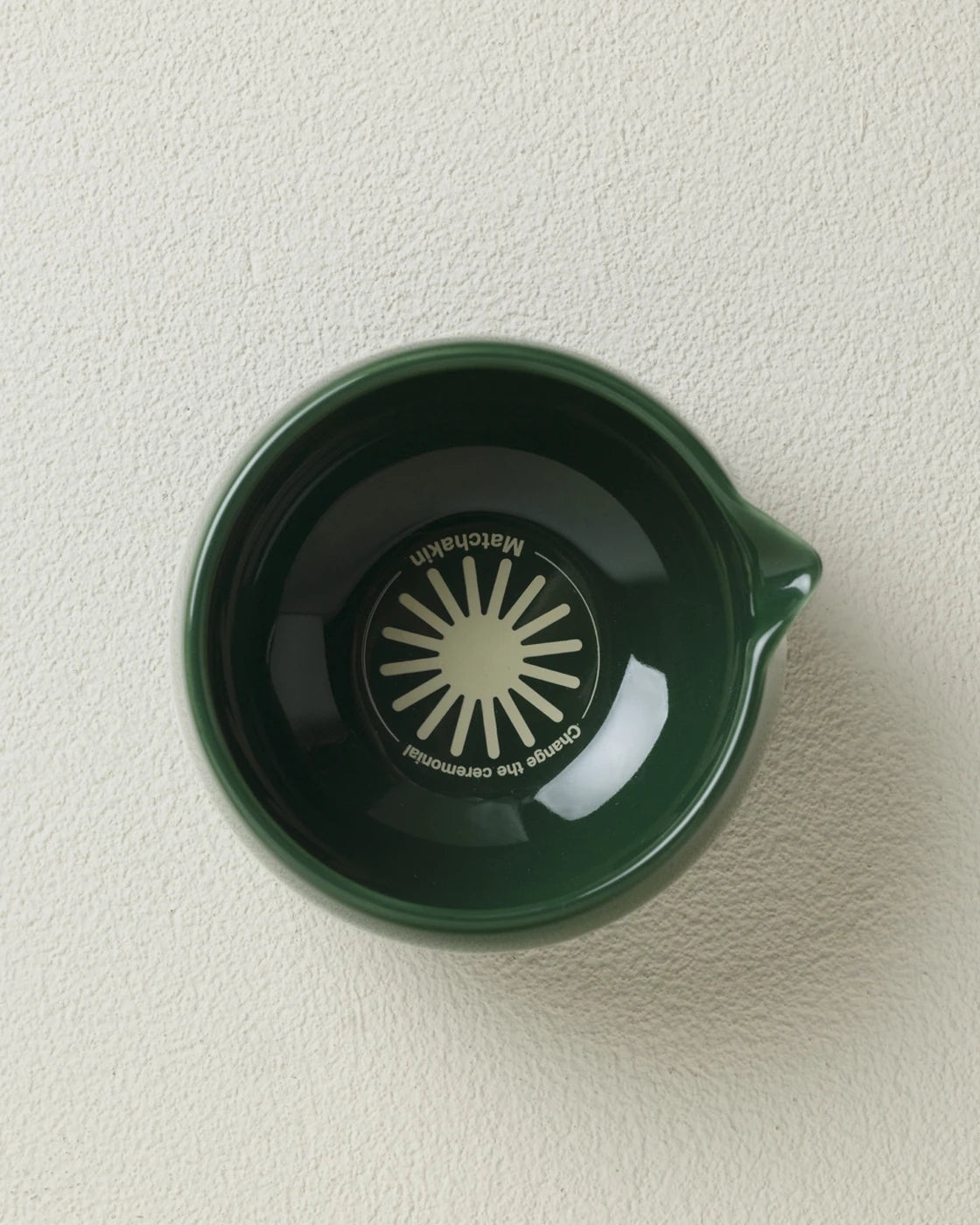 Matchakin matcha cup green ceramic mug with a sunburst design on a beige background