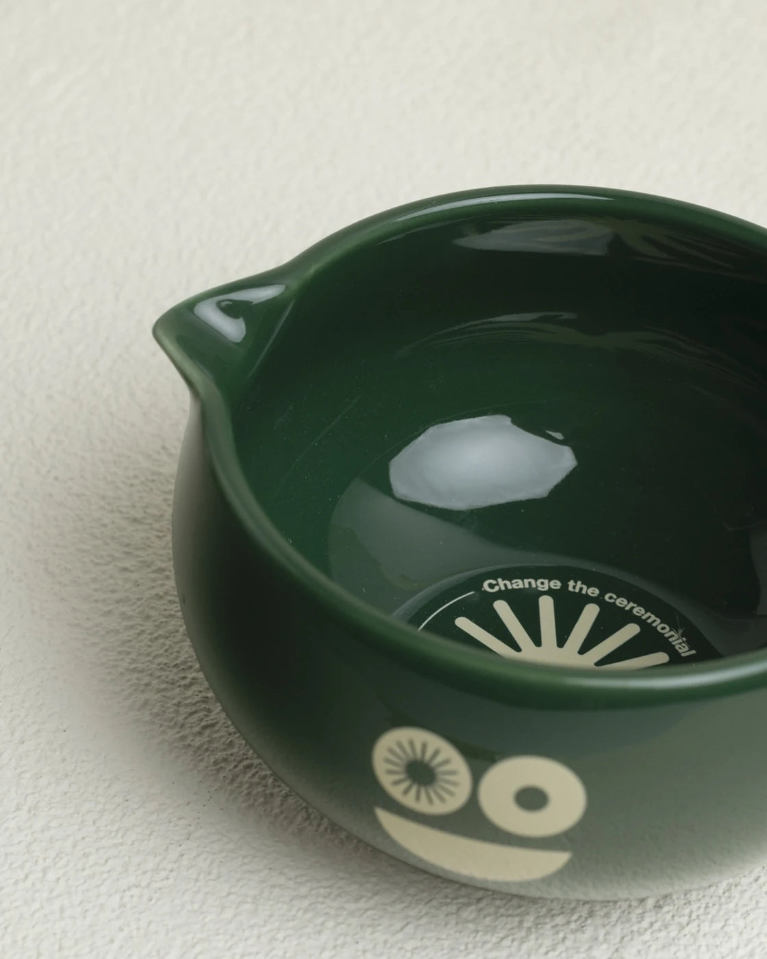 Green ceramic bowl with a face design on a white surface